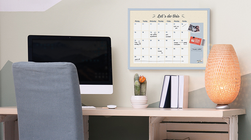 Home office with a monthly planner board on the wall.
